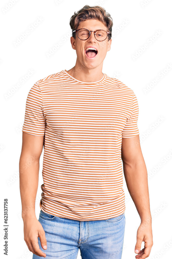 Fototapeta premium Young handsome man wearing casual clothes and glasses winking looking at the camera with sexy expression, cheerful and happy face.