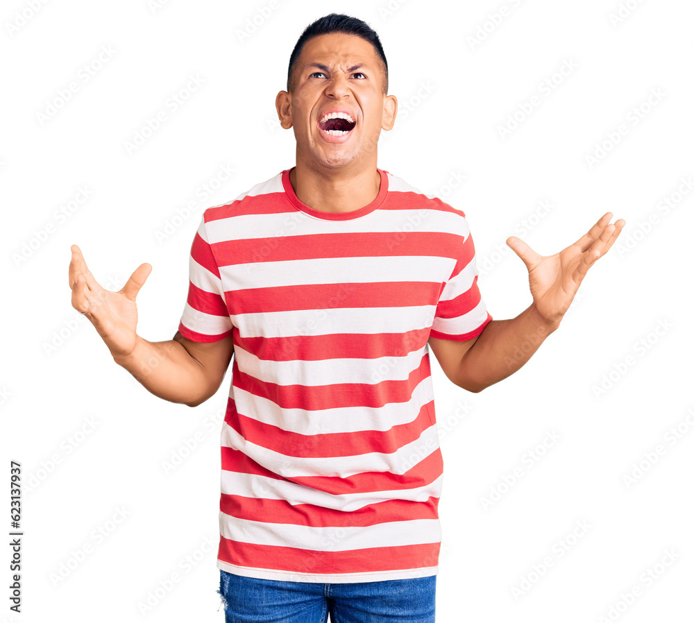 Young handsome latin man wearing casual clothes crazy and mad shouting and yelling with aggressive expression and arms raised. frustration concept. Young handsome latin man wearing casual clothes crazy and mad shouting and yelling with aggressive expression and arms raised. frustration concept.