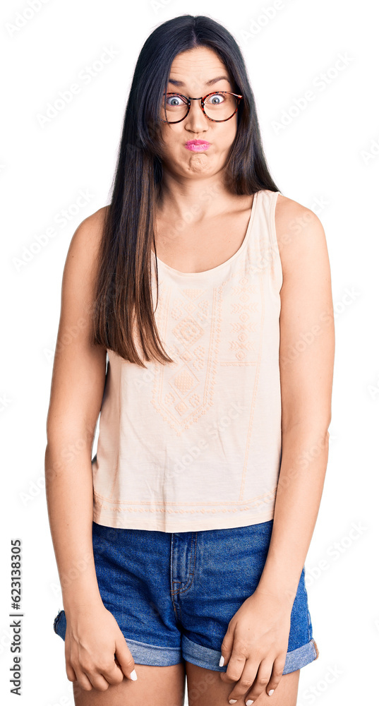 Young beautiful caucasian woman wearing casual clothes and glasses puffing cheeks with funny face. mouth inflated with air, crazy expression. Young beautiful caucasian woman wearing casual clothes and glasses puffing cheeks with funny face. mouth inflated with air, crazy expression.