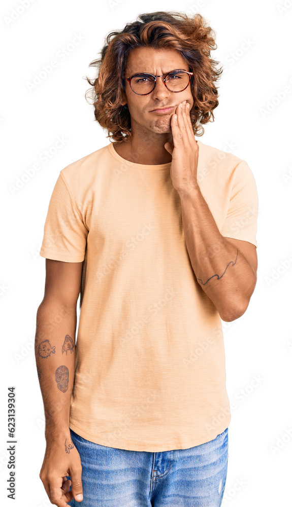 Young hispanic man wearing casual clothes and glasses touching mouth with hand with painful expression because of toothache or dental illness on teeth. dentist Young hispanic man wearing casual clothes and glasses touching mouth with hand with painful expression because of toothache or dental illness on teeth. dentist