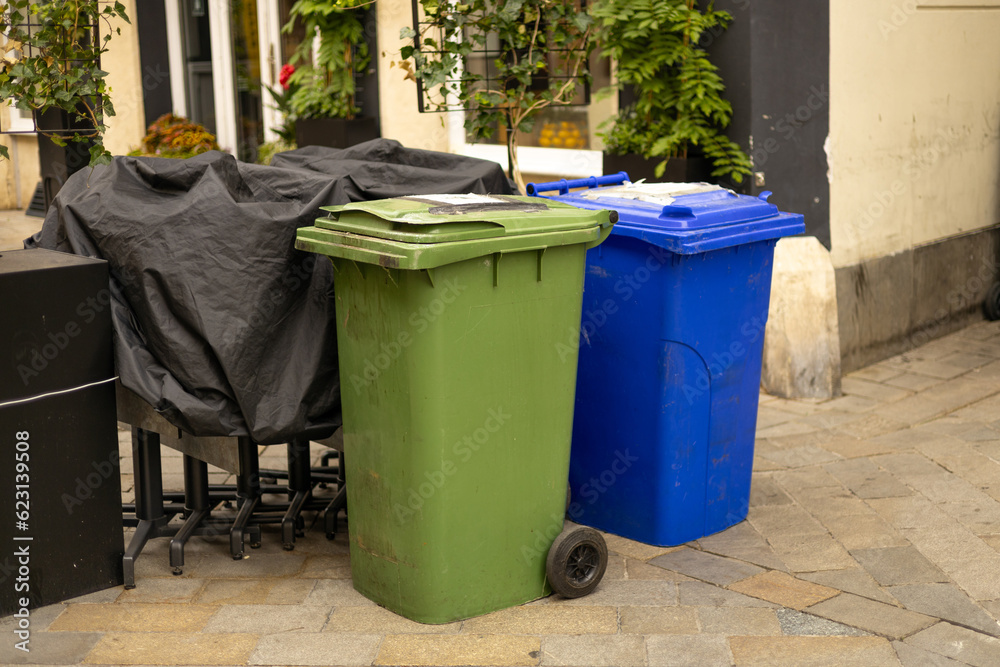Public trash on the side of the road. Plastic green and blue wheeled recycling rubbish bins beside the road for rubbish collection. Ecology concept Public trash on the side of the road. Plastic green and blue wheeled recycling rubbish bins beside the road for rubbish collection. Ecology concept
