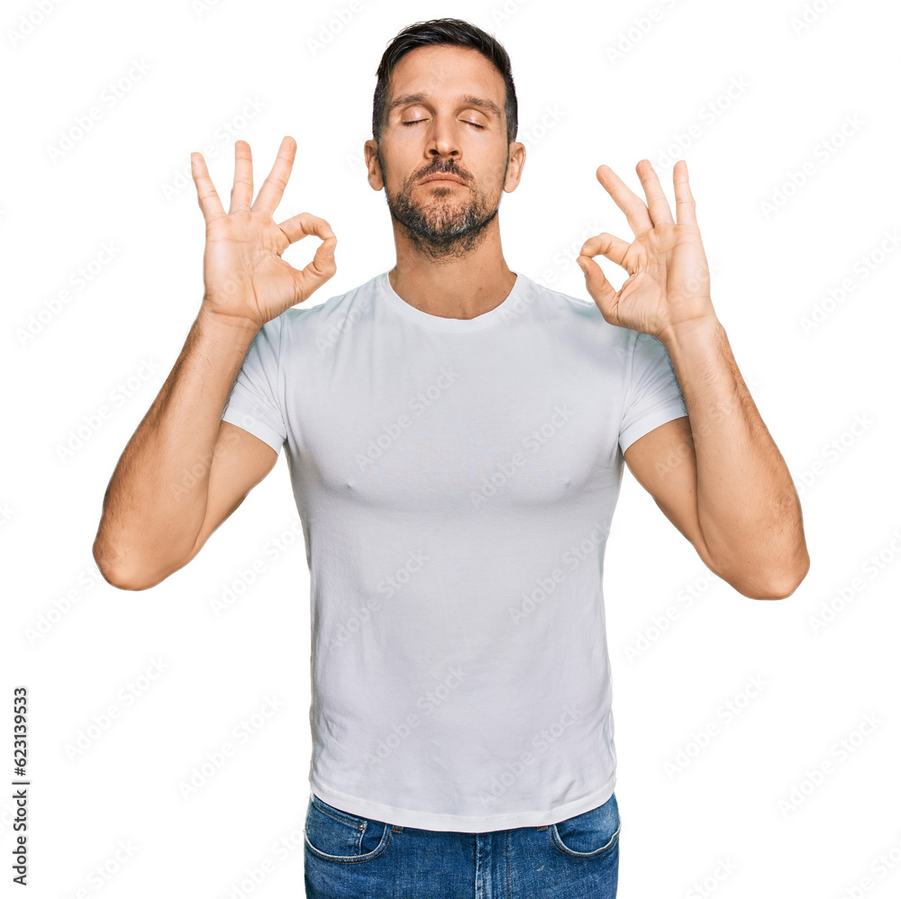 Fototapeta premium Handsome man with beard wearing casual white t shirt relax and smiling with eyes closed doing meditation gesture with fingers. yoga concept.