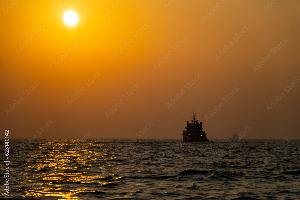 sunset creating ship silhouette offshore