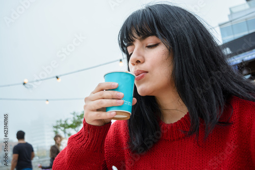 Canvastavla young Latin woman blowing on the coffee because it is too hot to drink