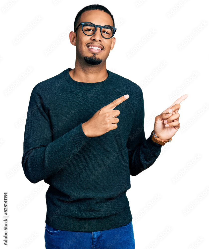 Young african american man wearing casual clothes and glasses smiling and looking at the camera pointing with two hands and fingers to the side. Young african american man wearing casual clothes and glasses smiling and looking at the camera pointing with two hands and fingers to the side.