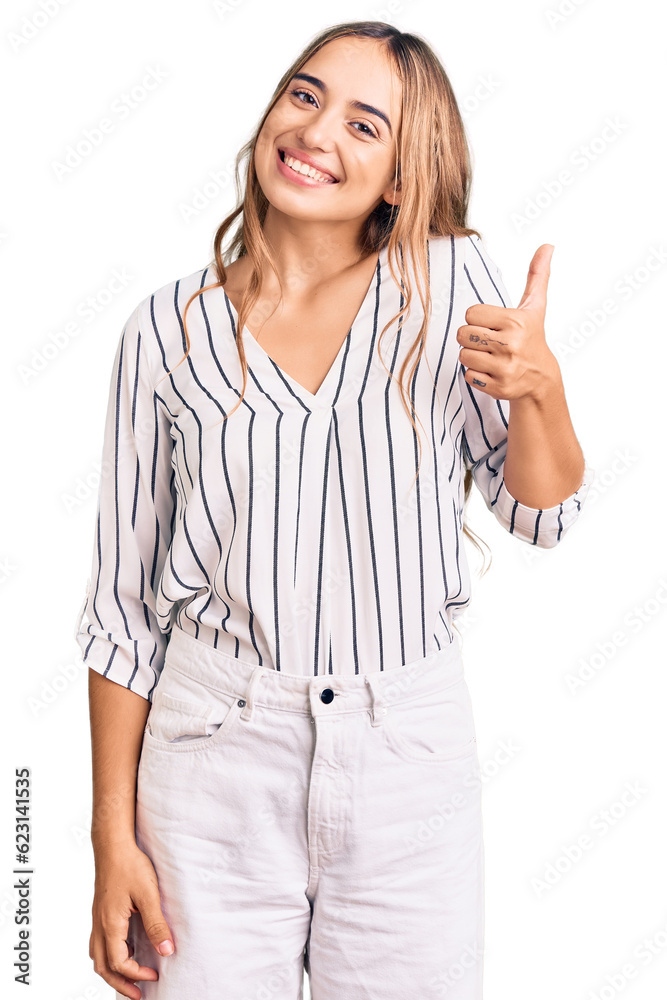 Young beautiful blonde woman wearing casual clothes smiling happy and positive, thumb up doing excellent and approval sign Young beautiful blonde woman wearing casual clothes smiling happy and positive, thumb up doing excellent and approval sign
