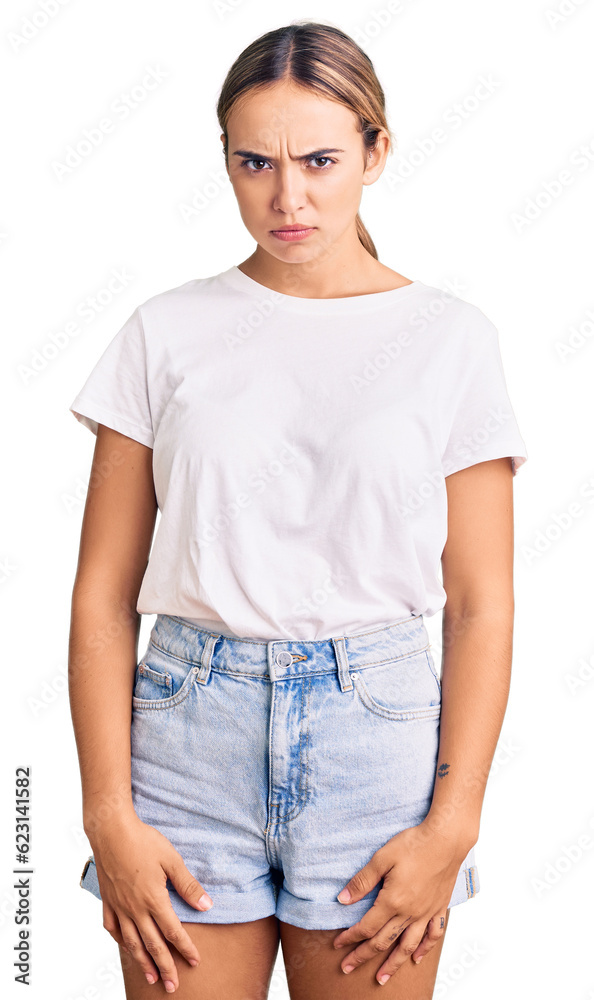 Young beautiful blonde woman wearing casual white tshirt skeptic and nervous, frowning upset because of problem. negative person. Young beautiful blonde woman wearing casual white tshirt skeptic and nervous, frowning upset because of problem. negative person.