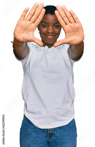 Young african american woman wearing casual white t shirt doing frame using hands palms and fingers, camera perspective