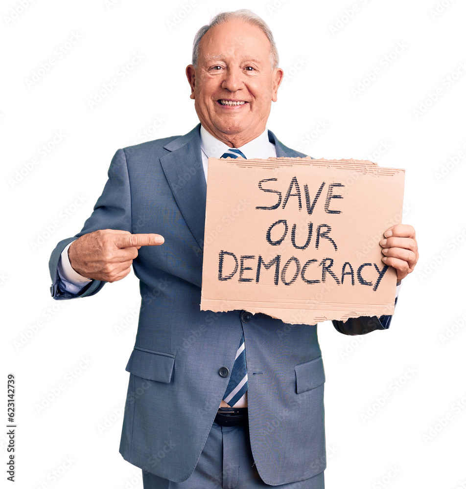 Senior handsome grey-haired man holding save our democracy cardboard banner smiling happy pointing with hand and finger Senior handsome grey-haired man holding save our democracy cardboard banner smiling happy pointing with hand and finger