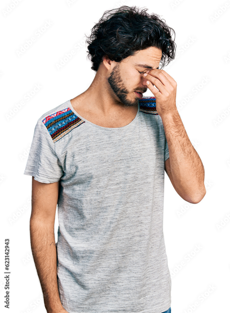 Young hispanic man wearing casual t shirt tired rubbing nose and eyes feeling fatigue and headache. stress and frustration concept. Young hispanic man wearing casual t shirt tired rubbing nose and eyes feeling fatigue and headache. stress and frustration concept.