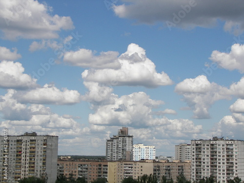 white cumulus clouds in the blue sky over high-rise city buildings