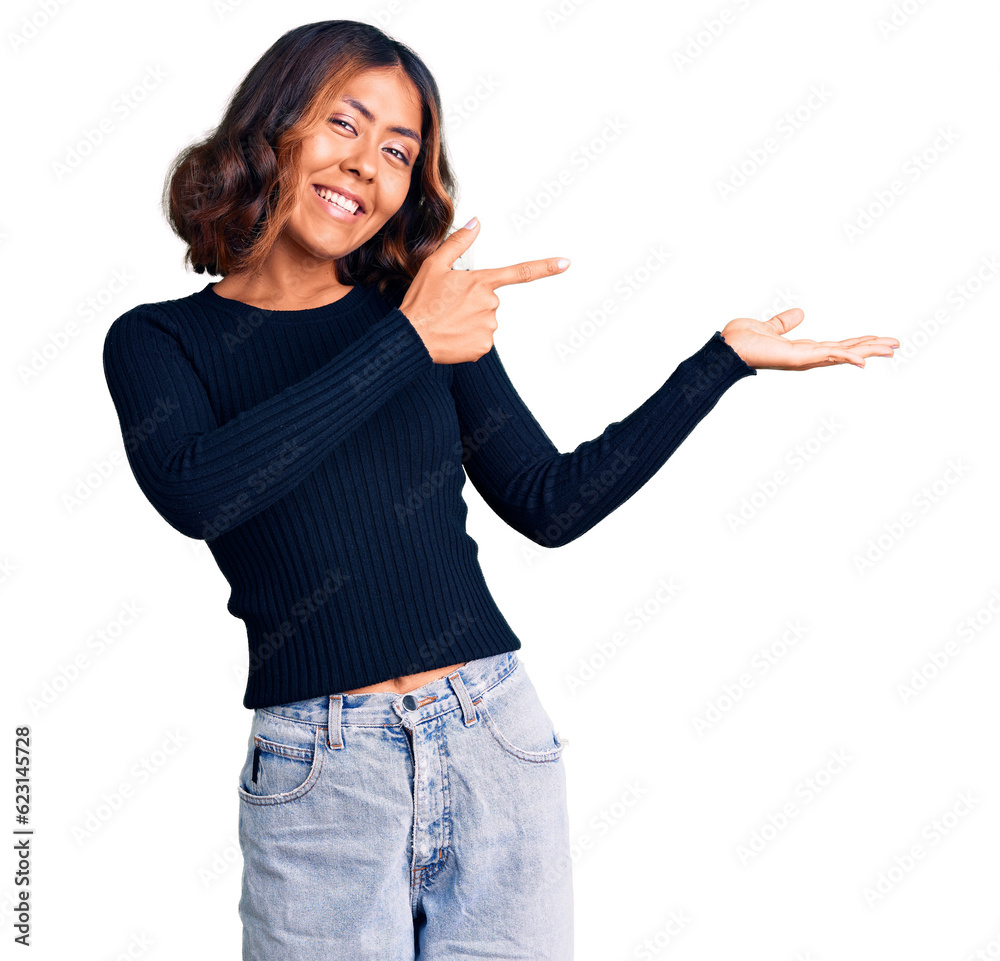 Young beautiful mixed race woman wearing casual clothes amazed and smiling to the camera while presenting with hand and pointing with finger. Young beautiful mixed race woman wearing casual clothes amazed and smiling to the camera while presenting with hand and pointing with finger.