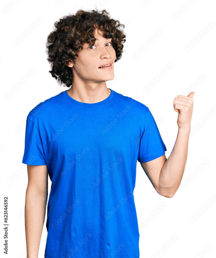 Caucasian teenager wearing casual clothes smiling with happy face looking and pointing to the side with thumb up.