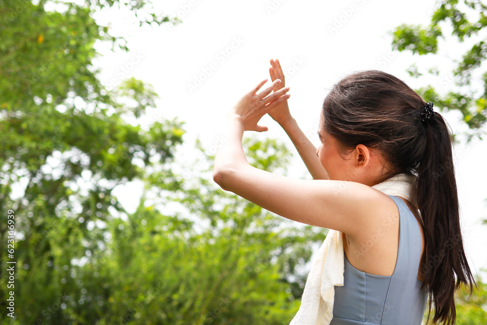 Asian woman exercising outdoors on a hot sunny day, body temperature above 40 degrees Celsius, using her hands to cover the sun. heat stroke Asian woman exercising outdoors on a hot sunny day, body temperature above 40 degrees Celsius, using her hands to cover the sun. heat stroke