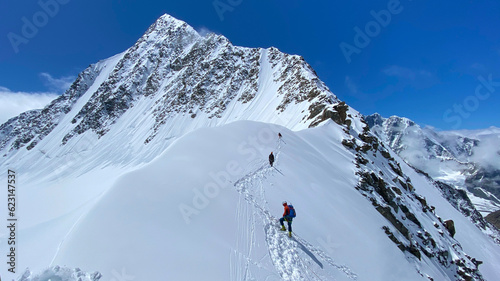 Three climbers are walking on a snow-covered mountain slope. Climbing Belukha. Altai Mountains.