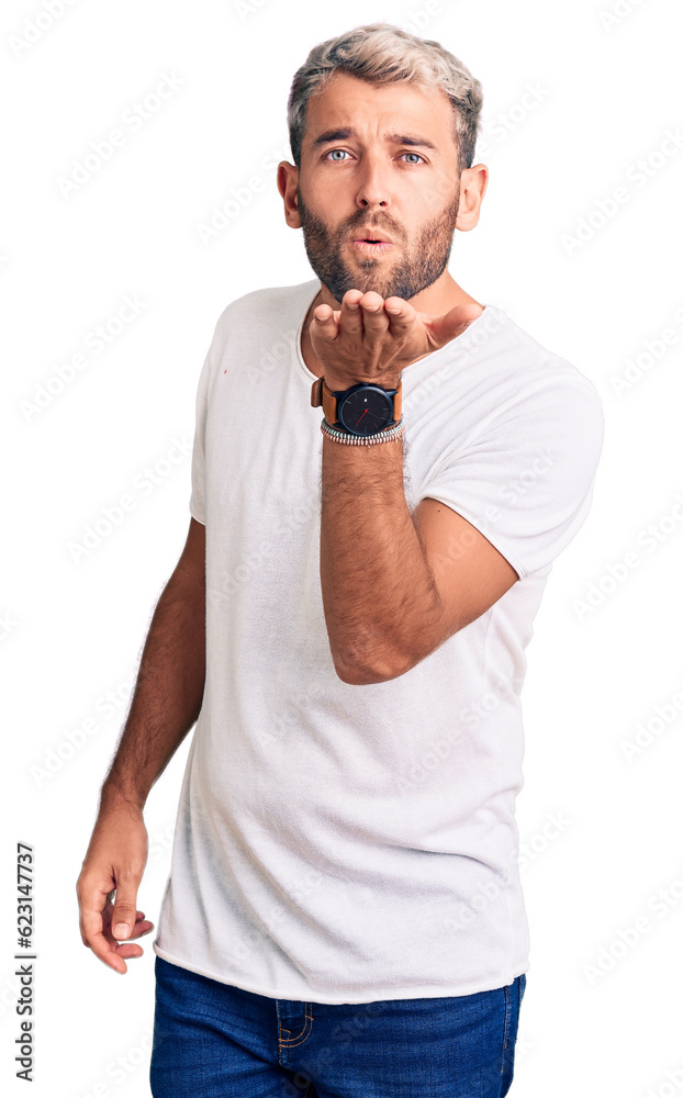 Young handsome blond man wearing casual t-shirt looking at the camera blowing a kiss with hand on air being lovely and sexy. love expression. Young handsome blond man wearing casual t-shirt looking at the camera blowing a kiss with hand on air being lovely and sexy. love expression.