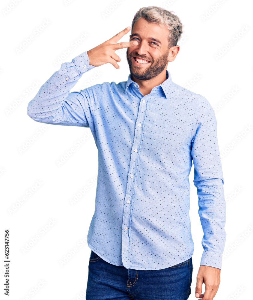 Young handsome blond man wearing elegant shirt doing peace symbol with fingers over face, smiling cheerful showing victory