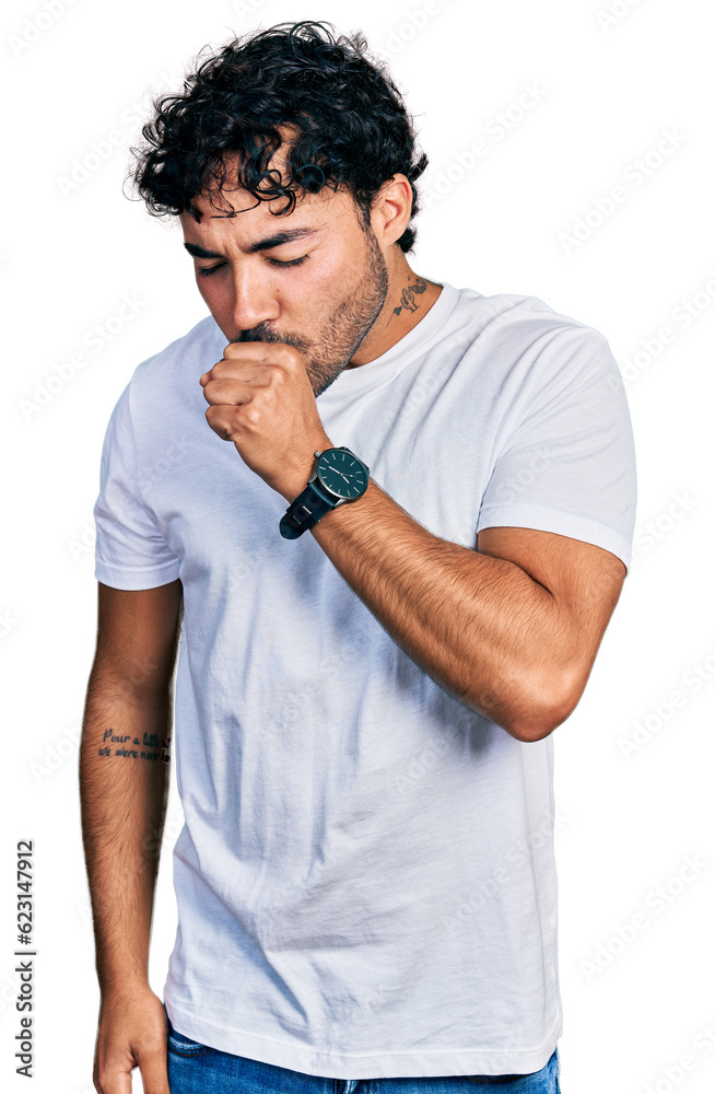 Hispanic young man with beard wearing casual white t shirt feeling unwell and coughing as symptom for cold or bronchitis. health care concept. Hispanic young man with beard wearing casual white t shirt feeling unwell and coughing as symptom for cold or bronchitis. health care concept.