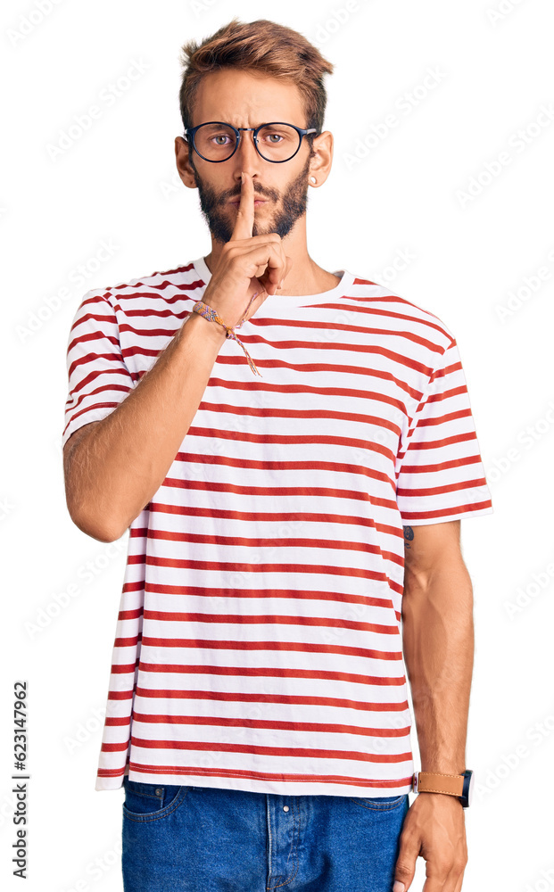 Handsome blond man with beard wearing casual clothes and glasses asking to be quiet with finger on lips. silence and secret concept. Handsome blond man with beard wearing casual clothes and glasses asking to be quiet with finger on lips. silence and secret concept.