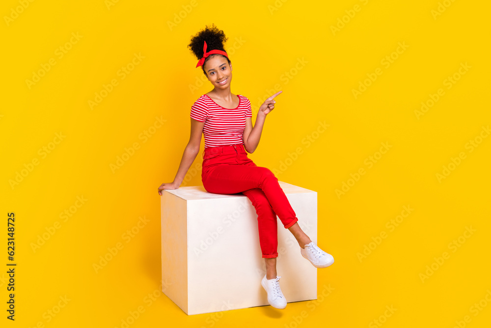 Full length photo of cheerful shiny lady wear striped red t-shirt pointing empty space isolated yellow color background
