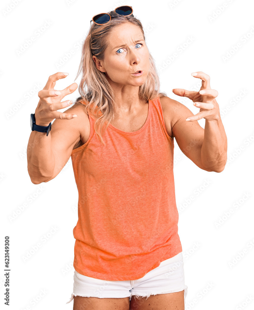 Middle age fit blonde woman wearing casual summer clothes and sunglasses shouting frustrated with rage, hands trying to strangle, yelling mad Middle age fit blonde woman wearing casual summer clothes and sunglasses shouting frustrated with rage, hands trying to strangle, yelling mad