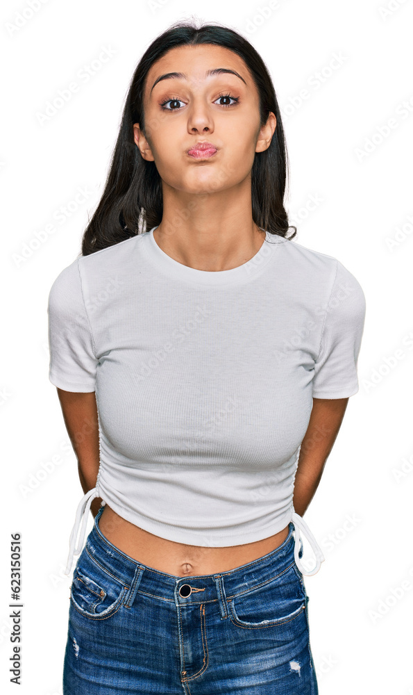 Fototapeta premium Young hispanic girl wearing casual white t shirt puffing cheeks with funny face. mouth inflated with air, crazy expression.