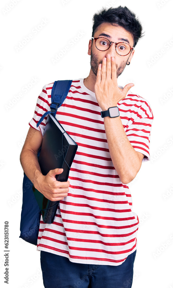 Young hispanic man wearing student backpack and glasses holding binder covering mouth with hand, shocked and afraid for mistake. surprised expression Young hispanic man wearing student backpack and glasses holding binder covering mouth with hand, shocked and afraid for mistake. surprised expression