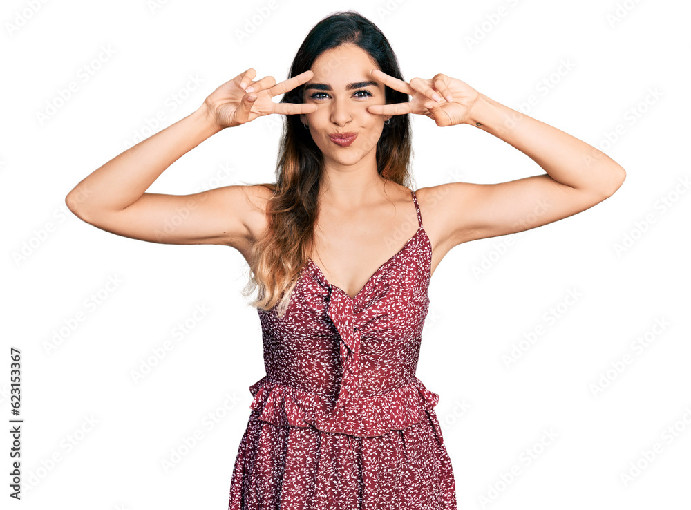 Beautiful hispanic woman wearing bohemian and hippie style doing peace symbol looking at the camera blowing a kiss being lovely and sexy. love expression. Beautiful hispanic woman wearing bohemian and hippie style doing peace symbol looking at the camera blowing a kiss being lovely and sexy. love expression.