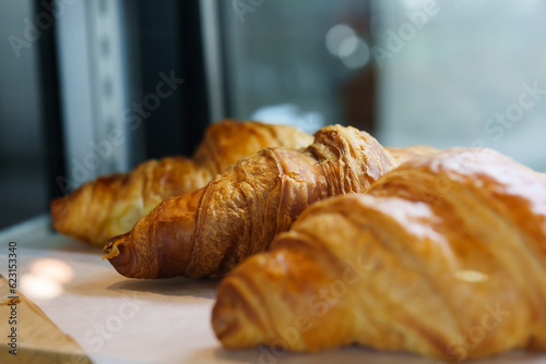 Close-up shot of delicious brown bread croissants Inside the shop, there are 3 machines ready for customers to come in and order.