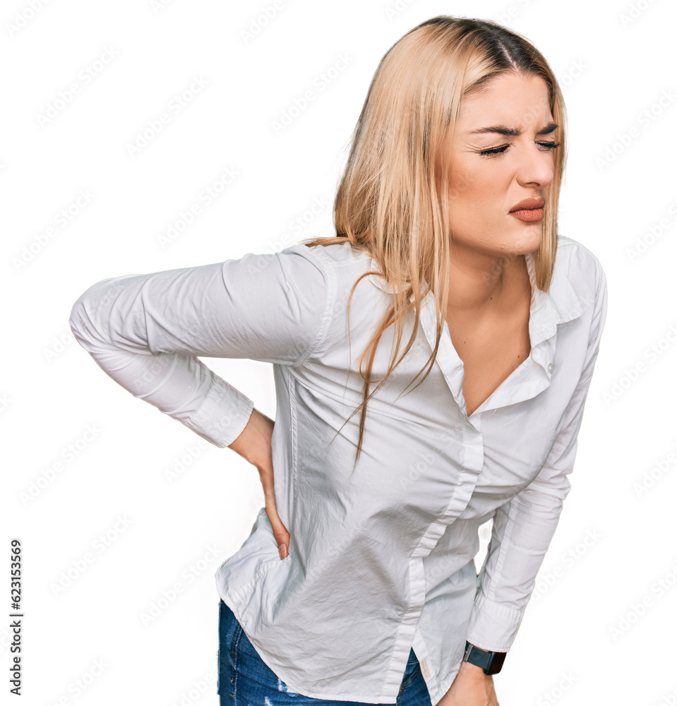 Young caucasian woman wearing casual clothes suffering of backache, touching back with hand, muscular pain Young caucasian woman wearing casual clothes suffering of backache, touching back with hand, muscular pain