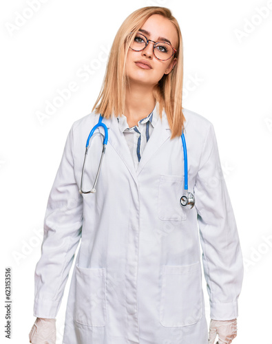 Beautiful caucasian woman wearing doctor uniform and stethoscope relaxed with serious expression on face. simple and natural looking at the camera.