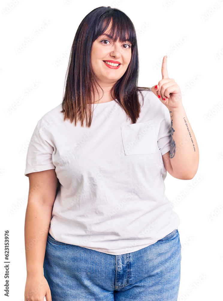 Young plus size woman wearing casual clothes pointing finger up with successful idea. exited and happy. number one. Young plus size woman wearing casual clothes pointing finger up with successful idea. exited and happy. number one.