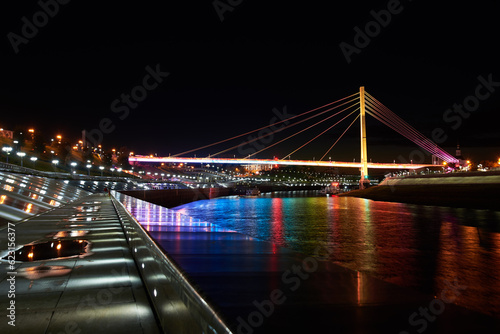 Beautiful view of the illuminated Bridge of Lovers over the Tura River at dusk, Tyumen, Russia