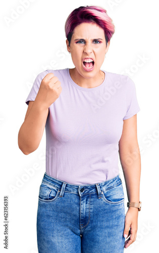 Young beautiful woman with pink hair wearing casual clothes angry and mad raising fist frustrated and furious while shouting with anger. rage and aggressive concept.