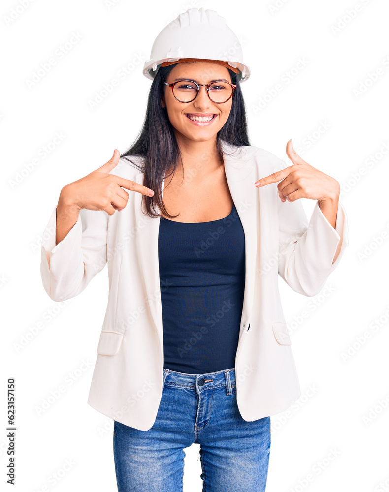 Young beautiful latin girl wearing architect hardhat and glasses looking confident with smile on face, pointing oneself with fingers proud and happy. Young beautiful latin girl wearing architect hardhat and glasses looking confident with smile on face, pointing oneself with fingers proud and happy.