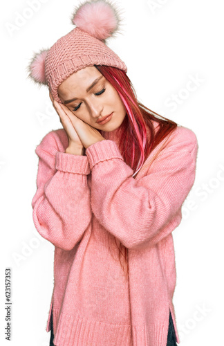 Young caucasian woman wearing casual clothes and wool cap sleeping tired dreaming and posing with hands together while smiling with closed eyes.