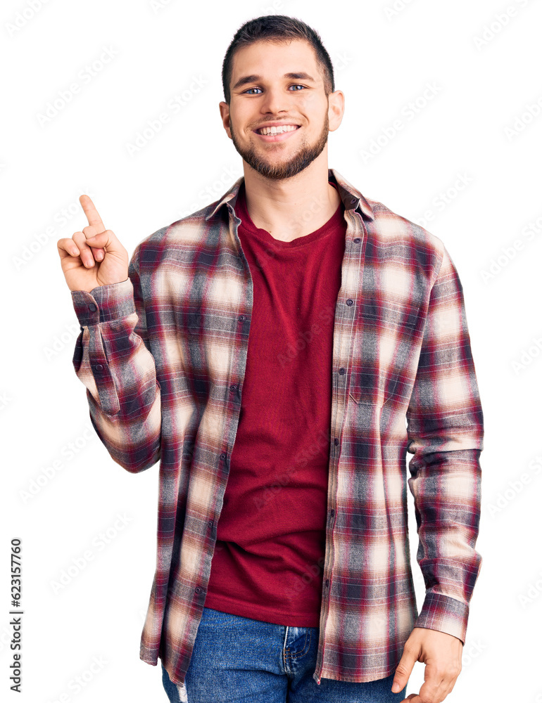 Naklejka premium Young handsome man wearing casual shirt with a big smile on face, pointing with hand finger to the side looking at the camera.