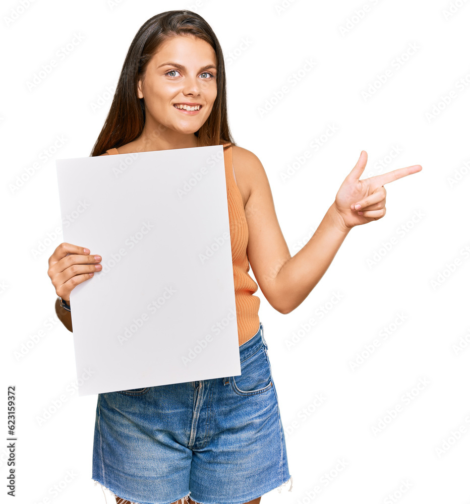 Young caucasian woman holding blank empty banner smiling happy pointing with hand and finger to the side Young caucasian woman holding blank empty banner smiling happy pointing with hand and finger to the side