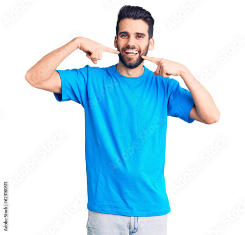 Young handsome man with beard wearing casual t-shirt smiling cheerful showing and pointing with fingers teeth and mouth. dental health concept.