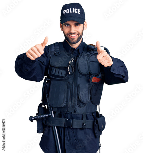 Young handsome man with beard wearing police uniform approving doing positive gesture with hand, thumbs up smiling and happy for success. winner gesture.