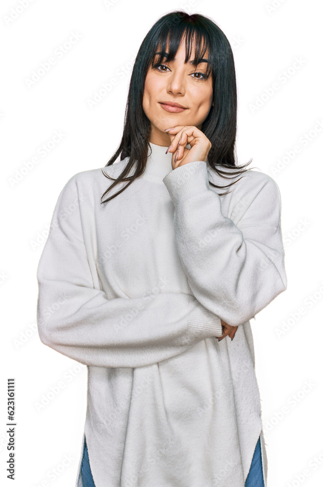 Young brunette woman with bangs wearing casual turtleneck sweater looking confident at the camera with smile with crossed arms and hand raised on chin. thinking positive. Young brunette woman with bangs wearing casual turtleneck sweater looking confident at the camera with smile with crossed arms and hand raised on chin. thinking positive.