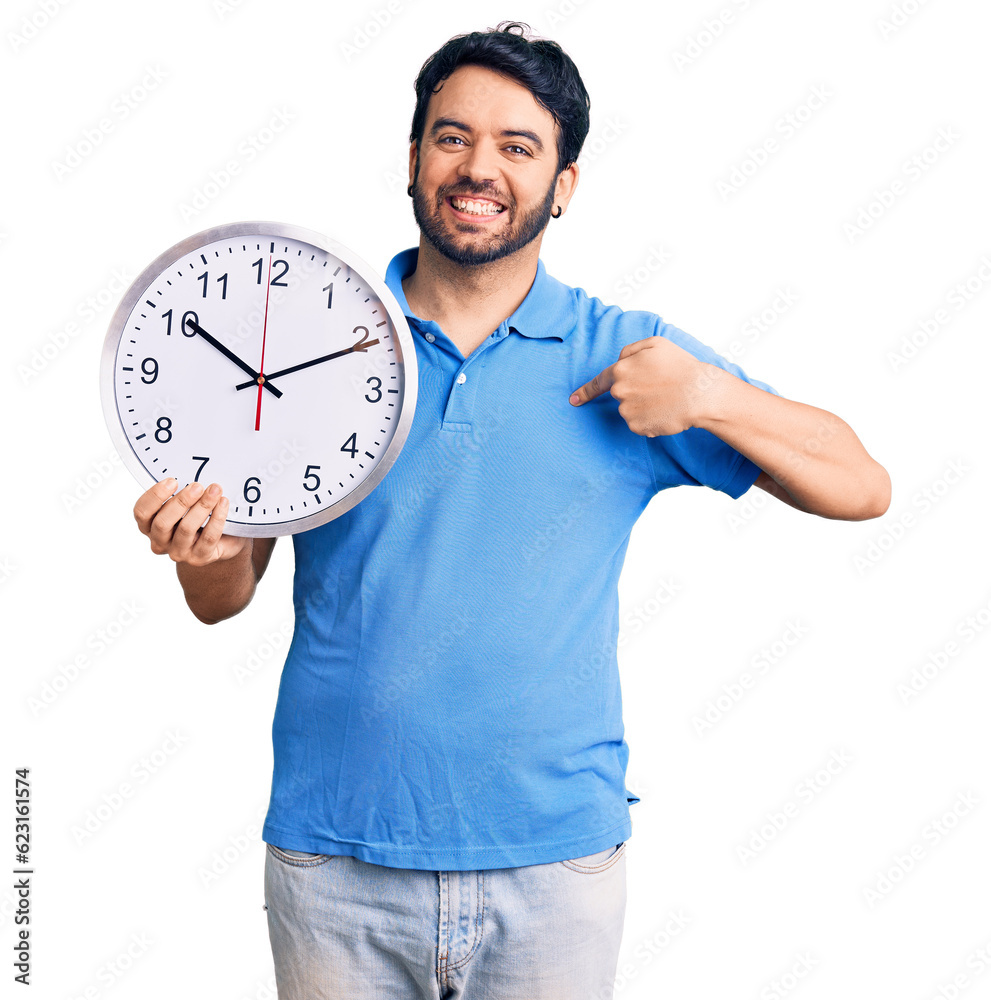 Young hispanic man holding big clock pointing finger to one self smiling happy and proud Young hispanic man holding big clock pointing finger to one self smiling happy and proud