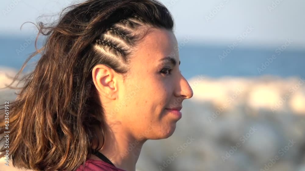 Close-up of a girl with braids, enjoying the sea breeze on the beach towards sunset Close-up of a girl with braids, enjoying the sea breeze on the beach towards sunset