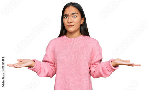 Obraz na plátně Young asian woman wearing casual winter sweater clueless and confused with open arms, no idea concept