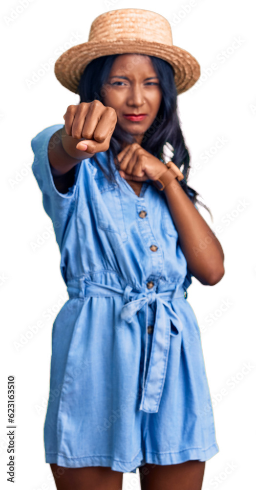 Young indian girl wearing summer hat punching fist to fight, aggressive and angry attack, threat and violence Young indian girl wearing summer hat punching fist to fight, aggressive and angry attack, threat and violence