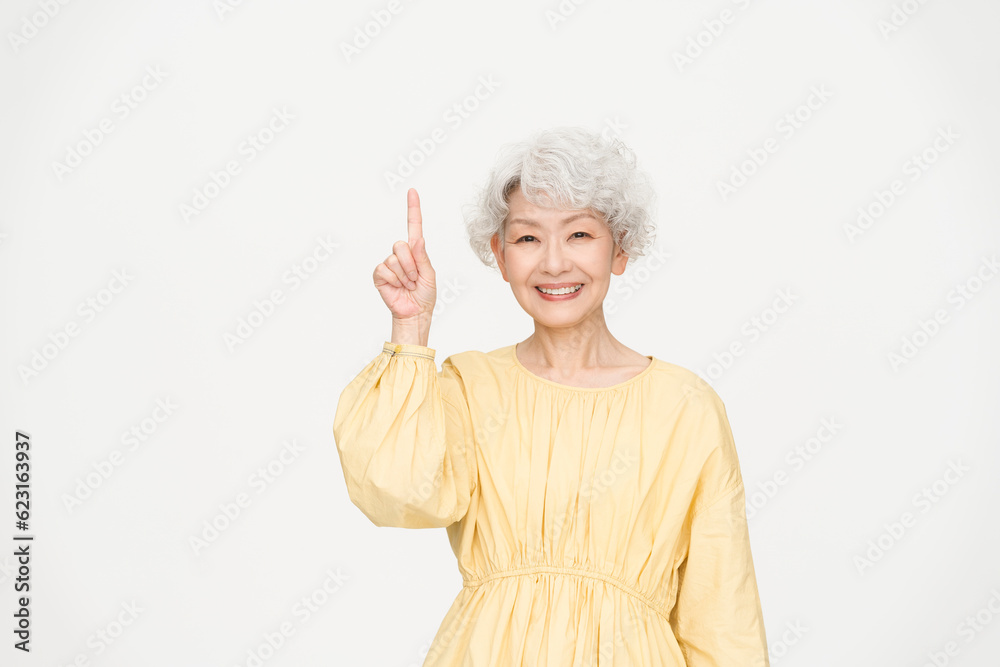 グレーヘアの健康的なシニア女性/スタジオ撮影白背景/指さし