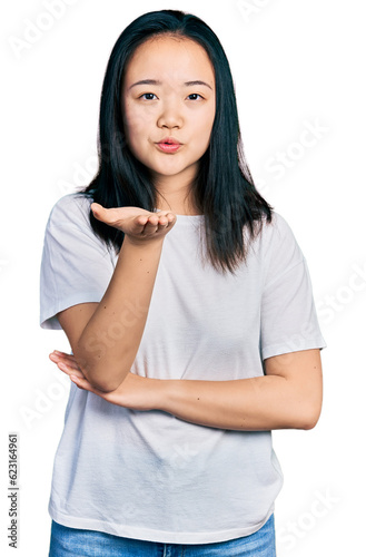 Young chinese woman wearing casual white t shirt looking at the camera blowing a kiss with hand on air being lovely and sexy. love expression. © Krakenimages.com