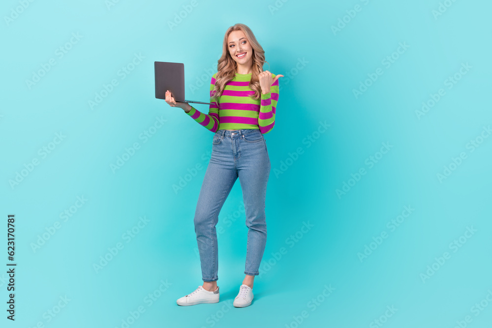 Full length photo of dreamy shiny woman dressed striped sweater typing email gadget thumb empty space isolated turquoise color background Full length photo of dreamy shiny woman dressed striped sweater typing email gadget thumb empty space isolated turquoise color background