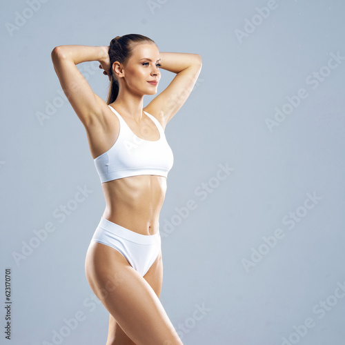 Young and beautiful slender girl in white swimsuit posing over white background. Healthcare, diet, sport and fitness concept.