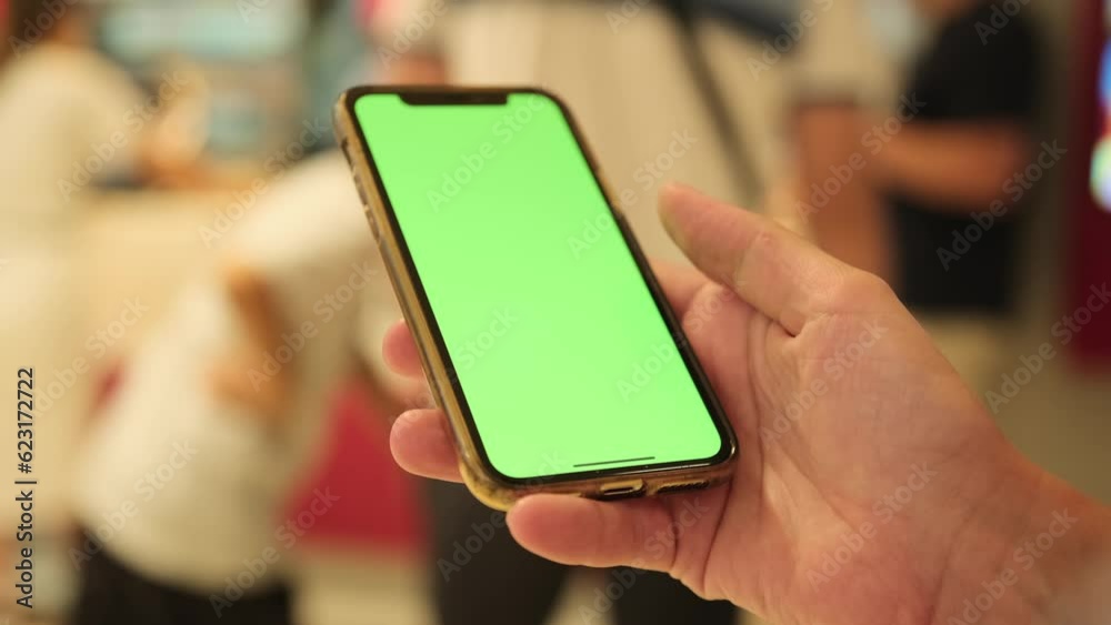 Woman looking through tape in phone, hand scrolls social media feed in smartphone with green screen, chromakey, close up. Modern wireless tech user concept.